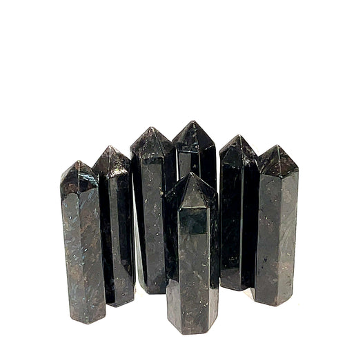 A collection of black Arfvedsonite gemstone towers arranged together on a white background, front, close up view. 