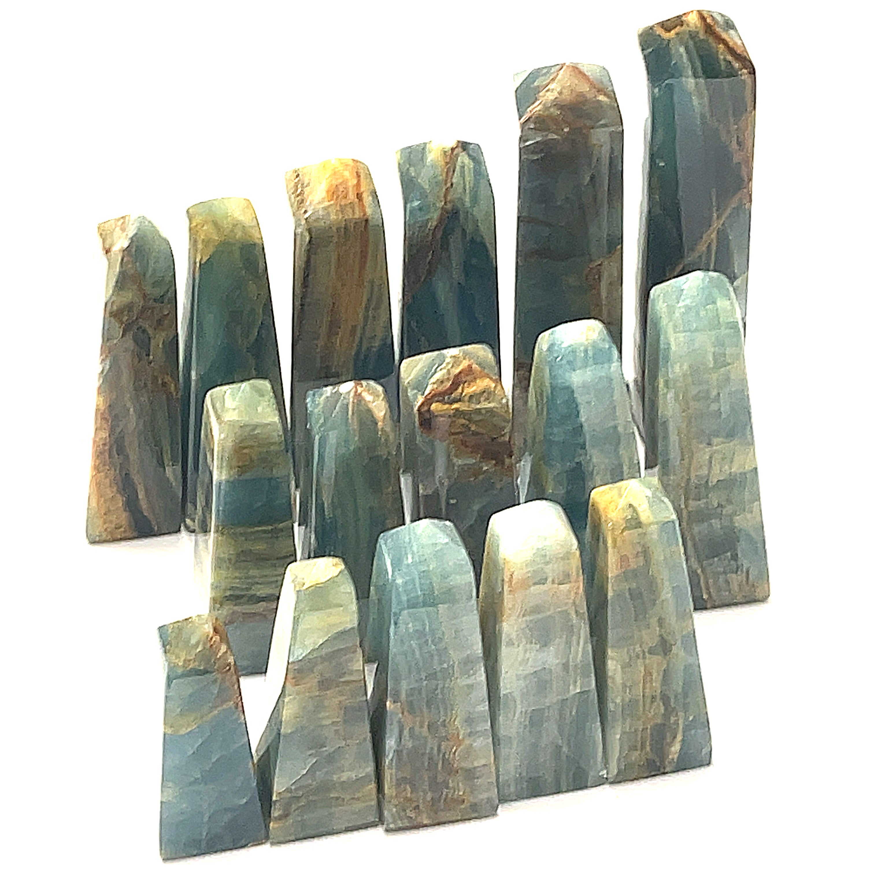 A collection of blue onyx gemstone towers displayed in a group on a white background, front overview. 