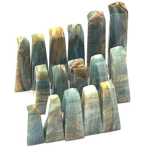 A collection of blue onyx gemstone towers displayed in a group on a white background, front overview. 