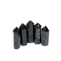 A collection of five black Arfvedsonite gemstone towers arranged together on a white background, front, close up view. 