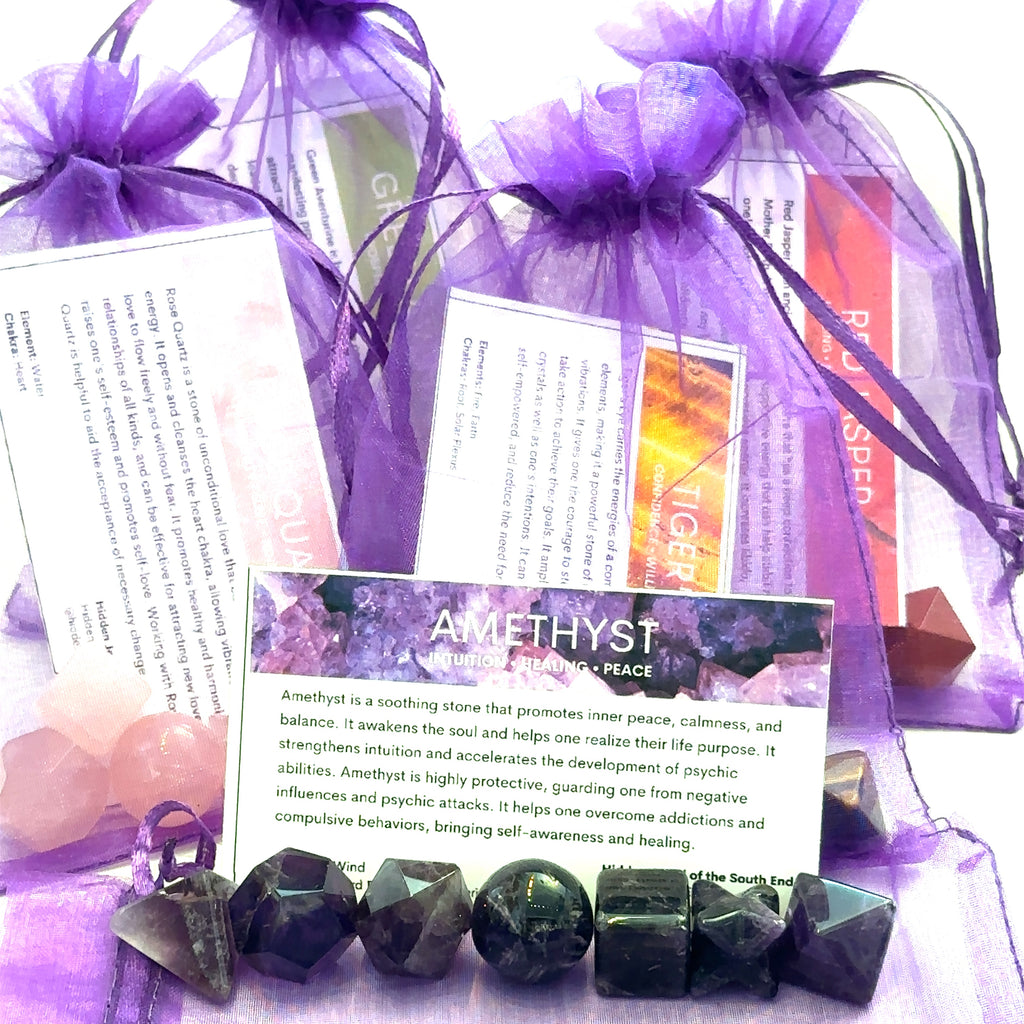 A collection of gemstone pieces arranged in a line with descriptive cards and packaging in the background, all set against a purple backdrop on a white overview