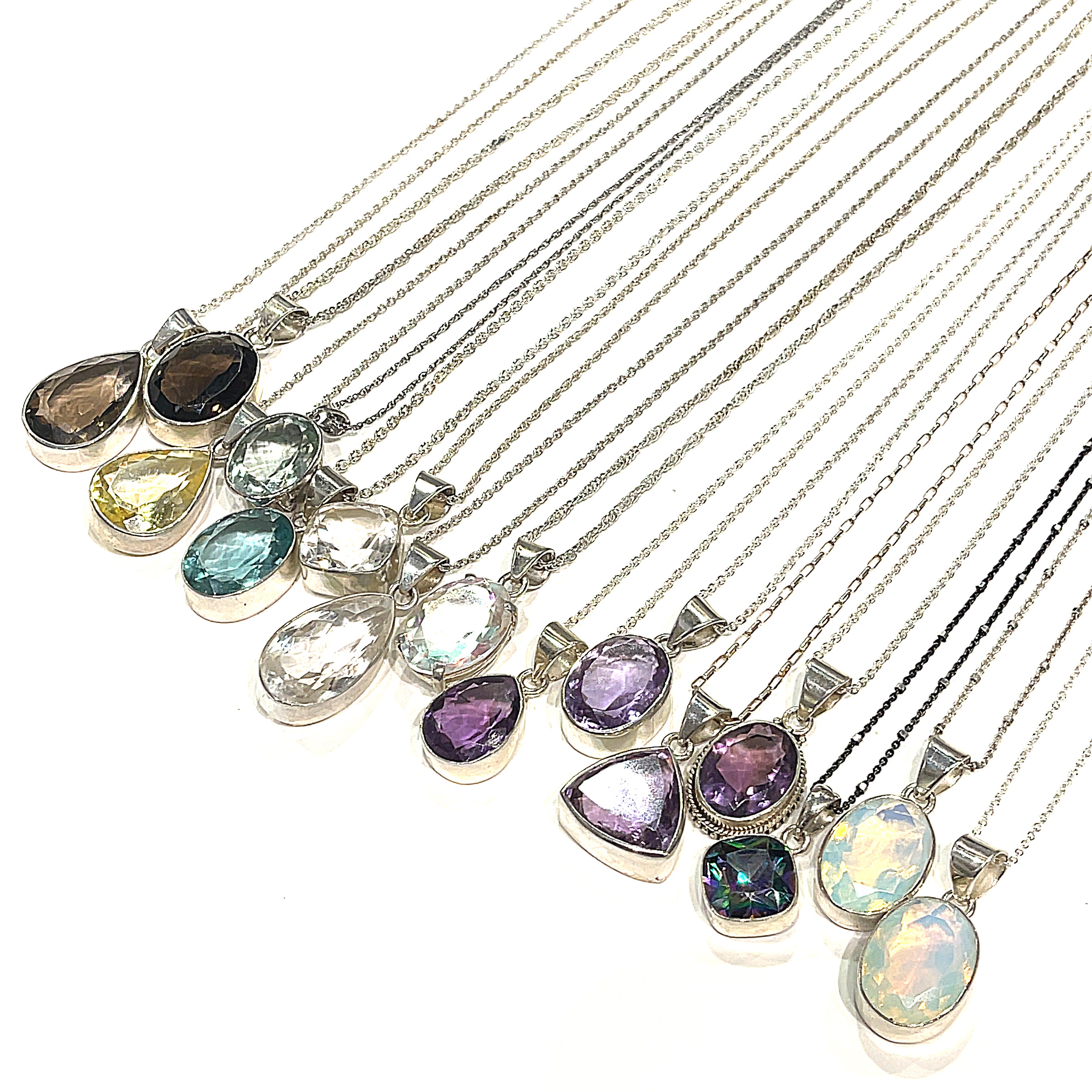A collection of gemstone sterling silver bezel set pendants on sterling silver chains in a diagonal line for a overview on a white background. 