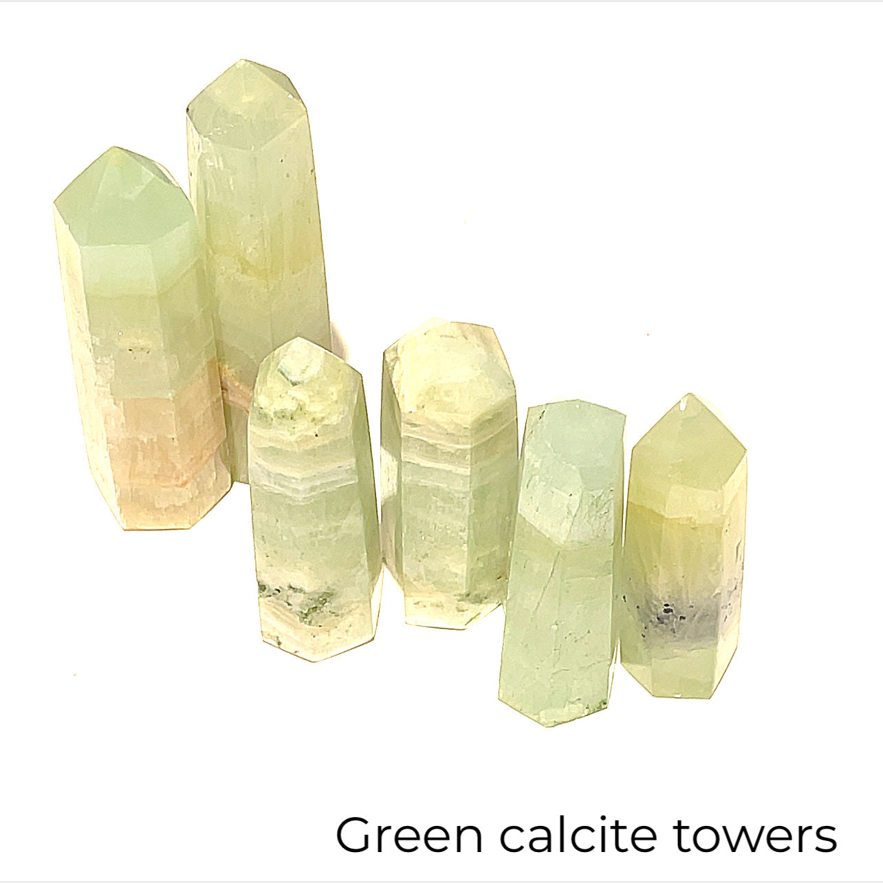 A collection of green calcite gemstone towers of various sizes arranged in a line on a white background, front overview.