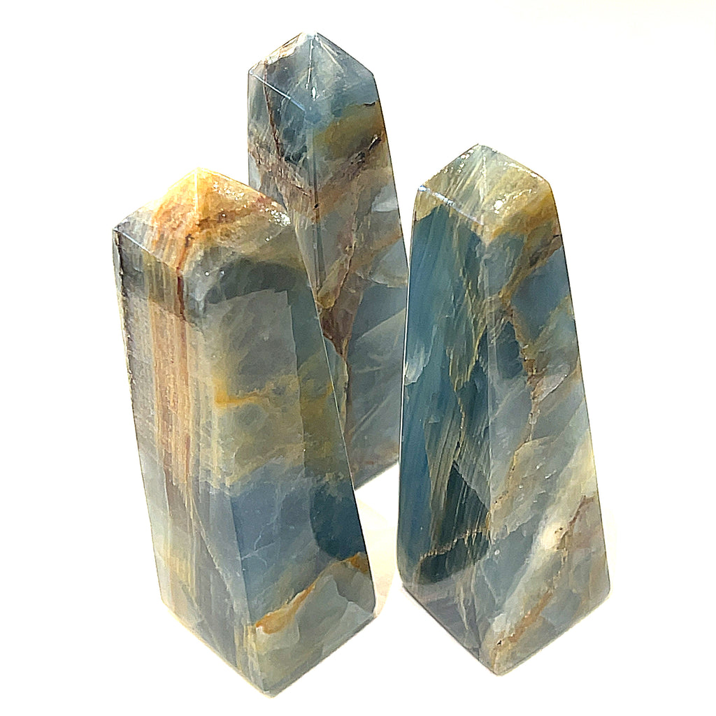 A collection of large sizes of  blue onyx gemstone towers displayed in a group on a white background, front overview.