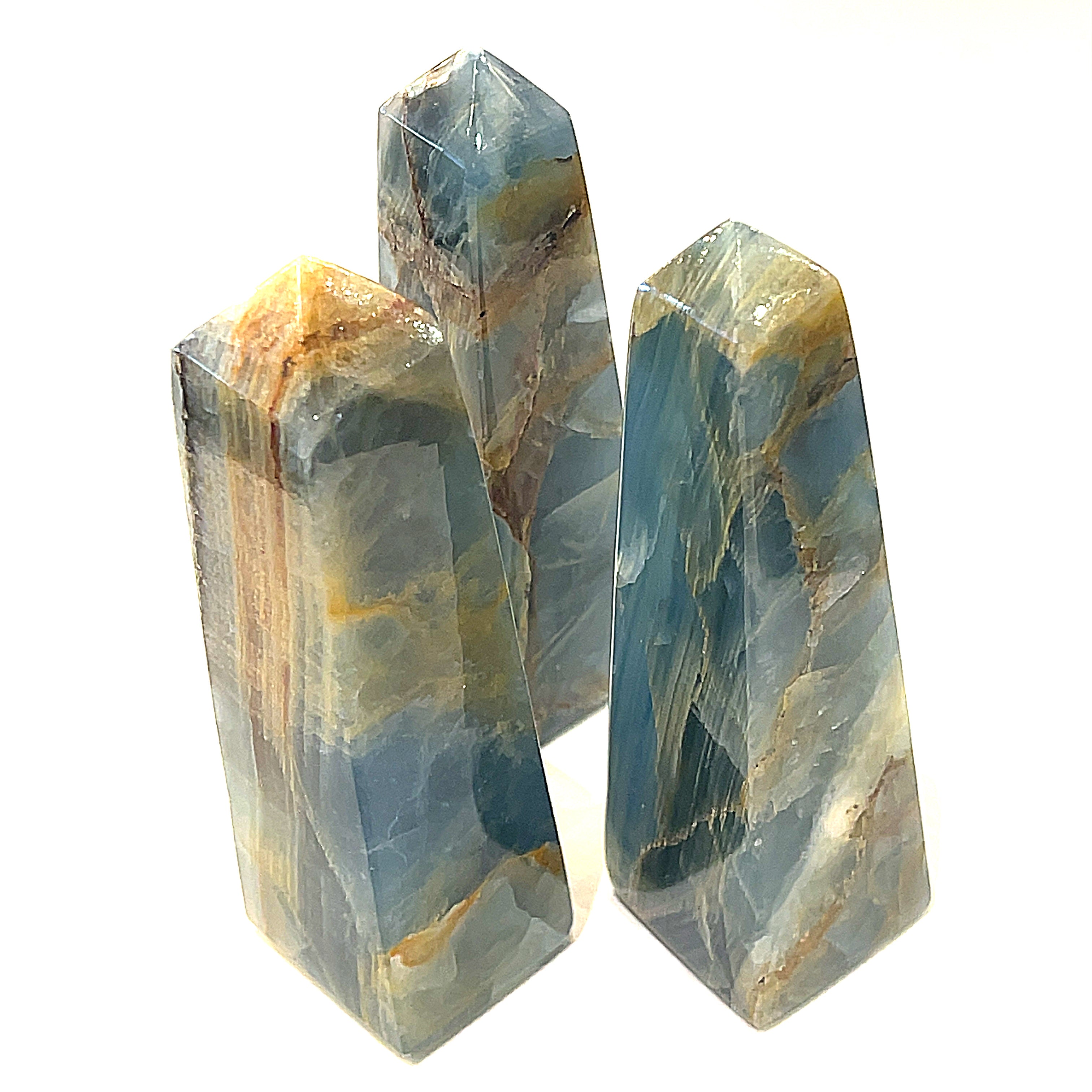 A collection of large sizes of  blue onyx gemstone towers displayed in a group on a white background, front overview.