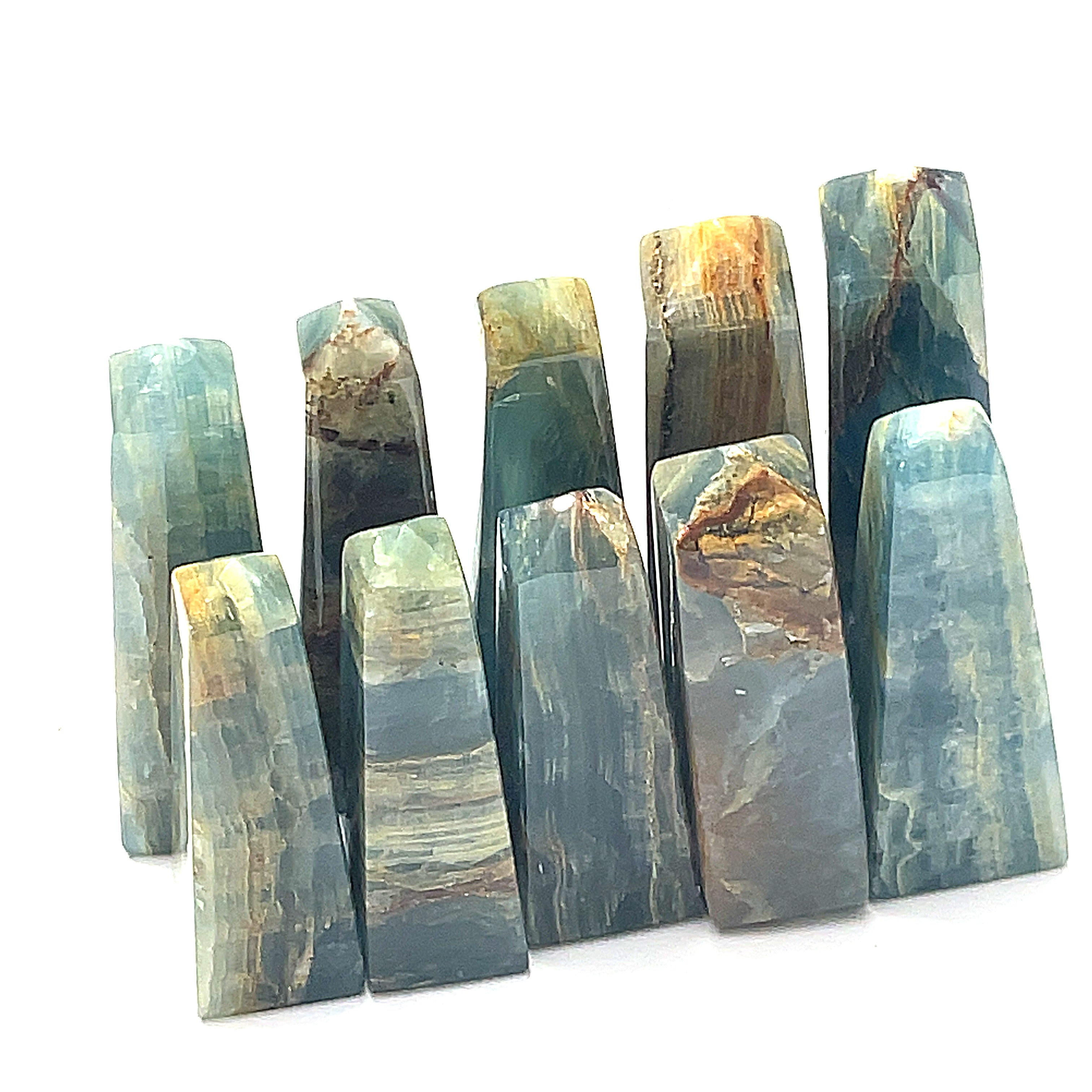 A collection of medium sizes of  blue onyx gemstone towers displayed in a group on a white background, front overview.