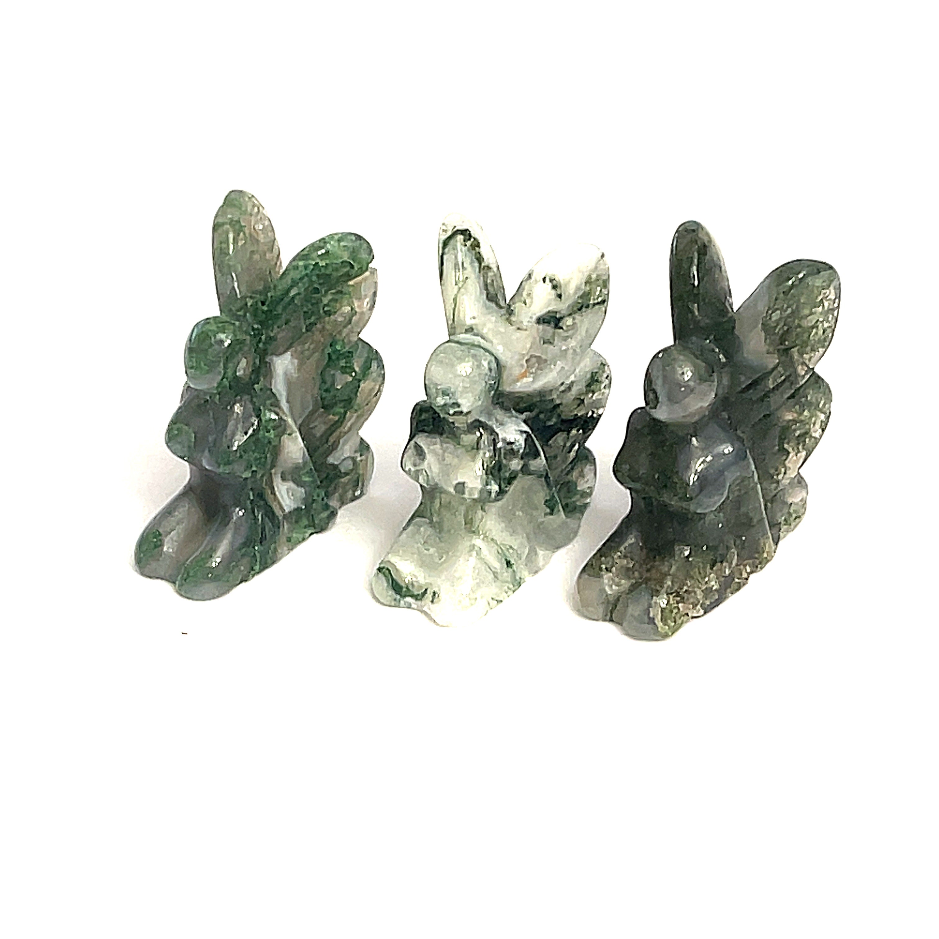 A collection of miniature gemstone carvings in, each resembling a fairy sitting with their hands on their lap, Moss Agate displayed on a white background, front view. 