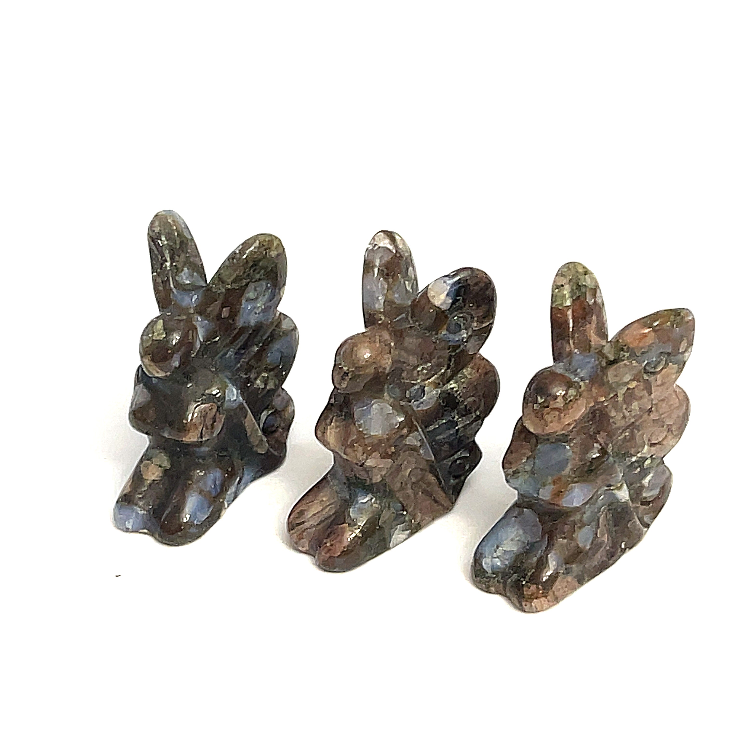 A collection of miniature gemstone carvings in, each resembling a fairy sitting with their hands on their lap, Yooperlite displayed on a white background, front view. 