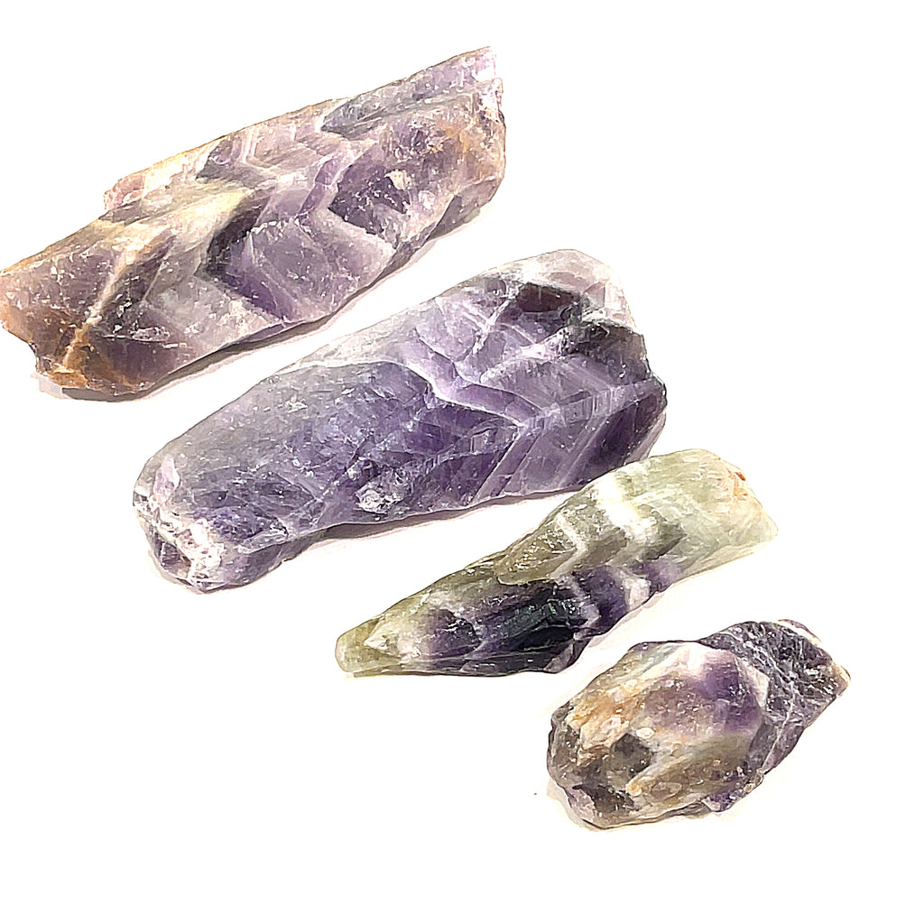 A collection of raw Amethyst or Prasiolite gemstones on a white background, front overview.