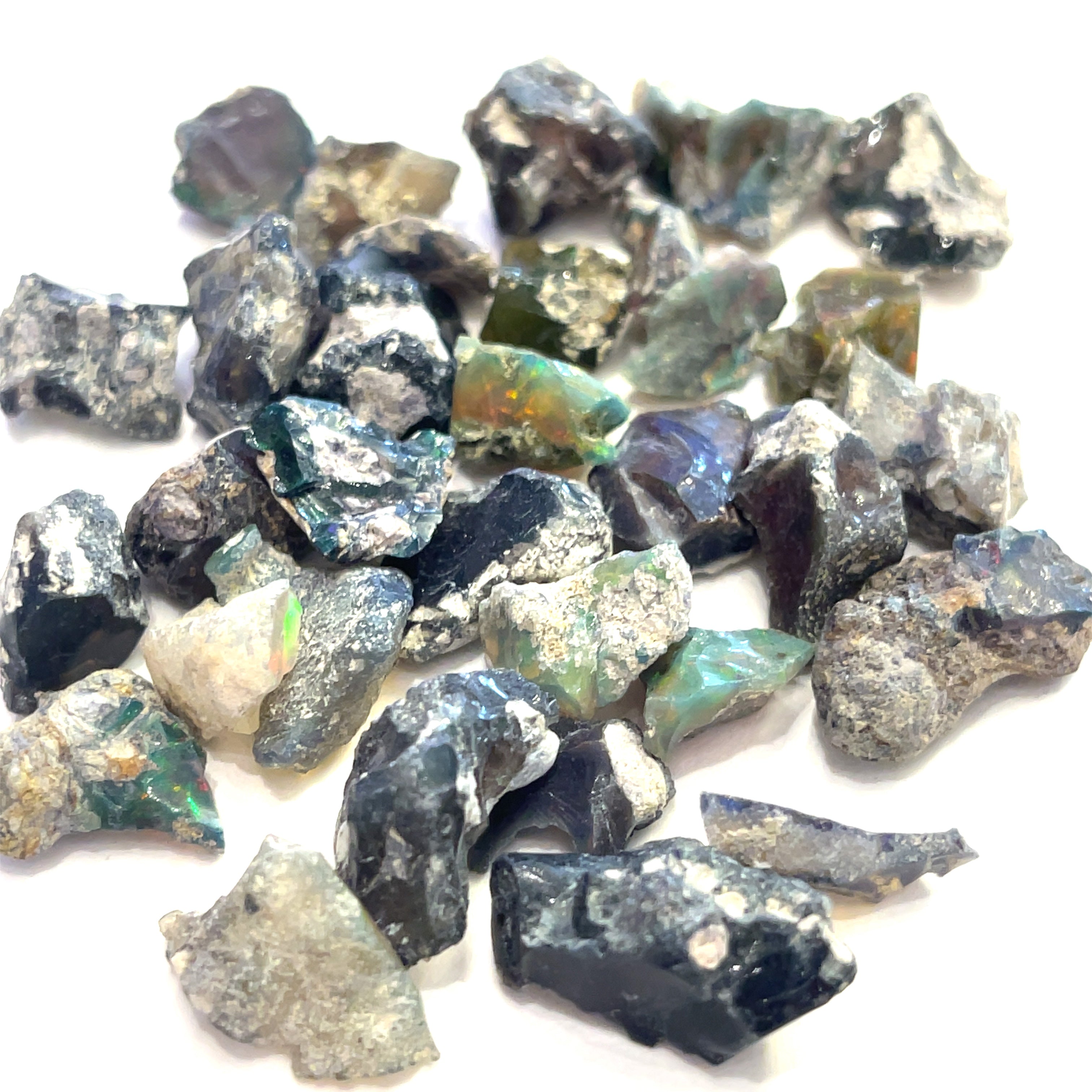 A collection of raw Ethiopian white  & black opal gemstones displayed on a white background, front overview size (XS)