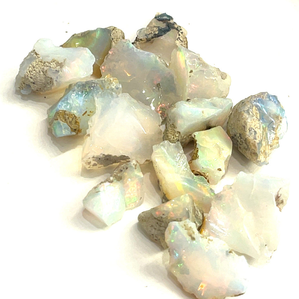 A collection of raw Ethiopian white opal gemstones displayed on a white background, front overview. 