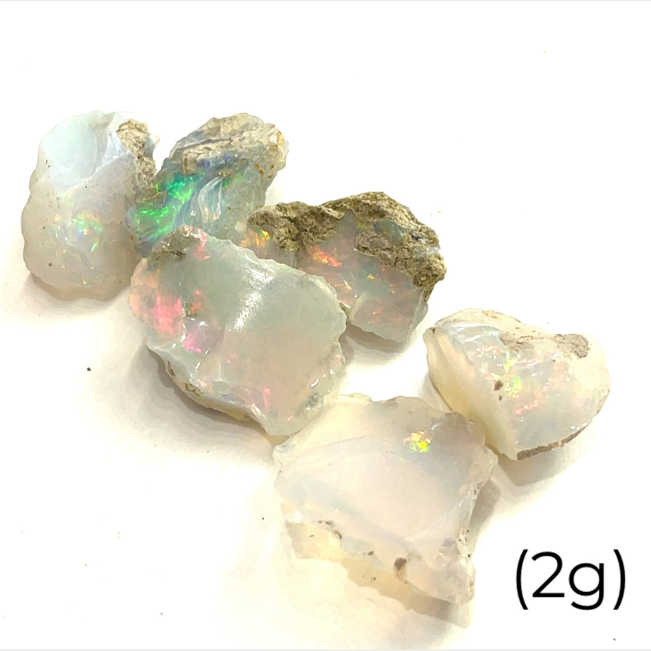 A collection of raw Ethiopian white opal gemstones displayed on a white background, front overview size (2g)