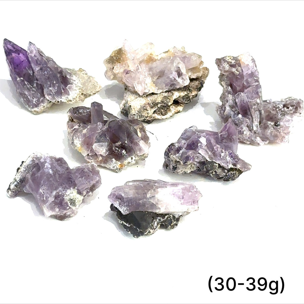 A collection of raw Guerrero Amethyst gemstones with varying crystal structures, predominantly in purple color, against a white background, with sizes ranging from 30 to 39g, front overview