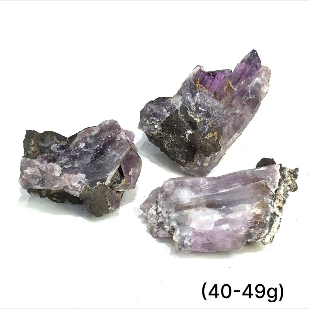 A collection of raw Guerrero Amethyst gemstones with varying crystal structures, predominantly in purple color, against a white background, with sizes ranging from 40 to 49g, front overview
