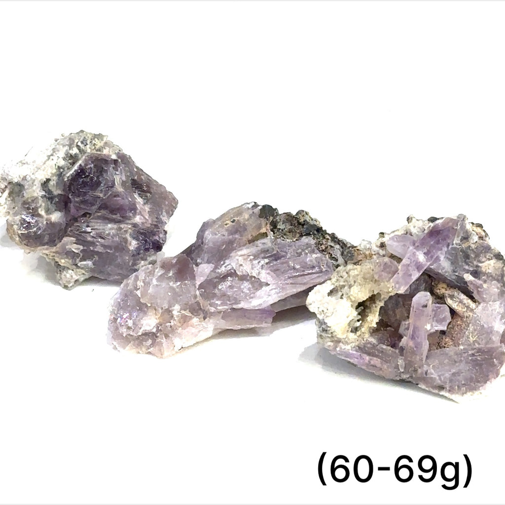 A collection of raw Guerrero Amethyst gemstones with varying crystal structures, predominantly in purple color, against a white background, with sizes ranging from 60 to 69g, front overview.