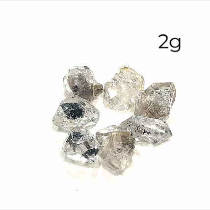 A collection of raw Herkimer diamond gemstones (2g) displayed on a white background, front overview. 