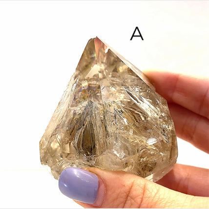 A collection of raw Herkimer diamond gemstones (A) displayed on a white background, front, in models finger tips  overview. 