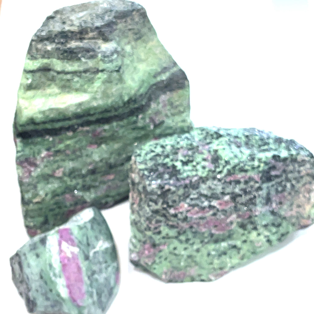 A collection of raw Ruby in Zoisite gemstones with a greenish tinge and visible pink inclusions on a white background, front view.