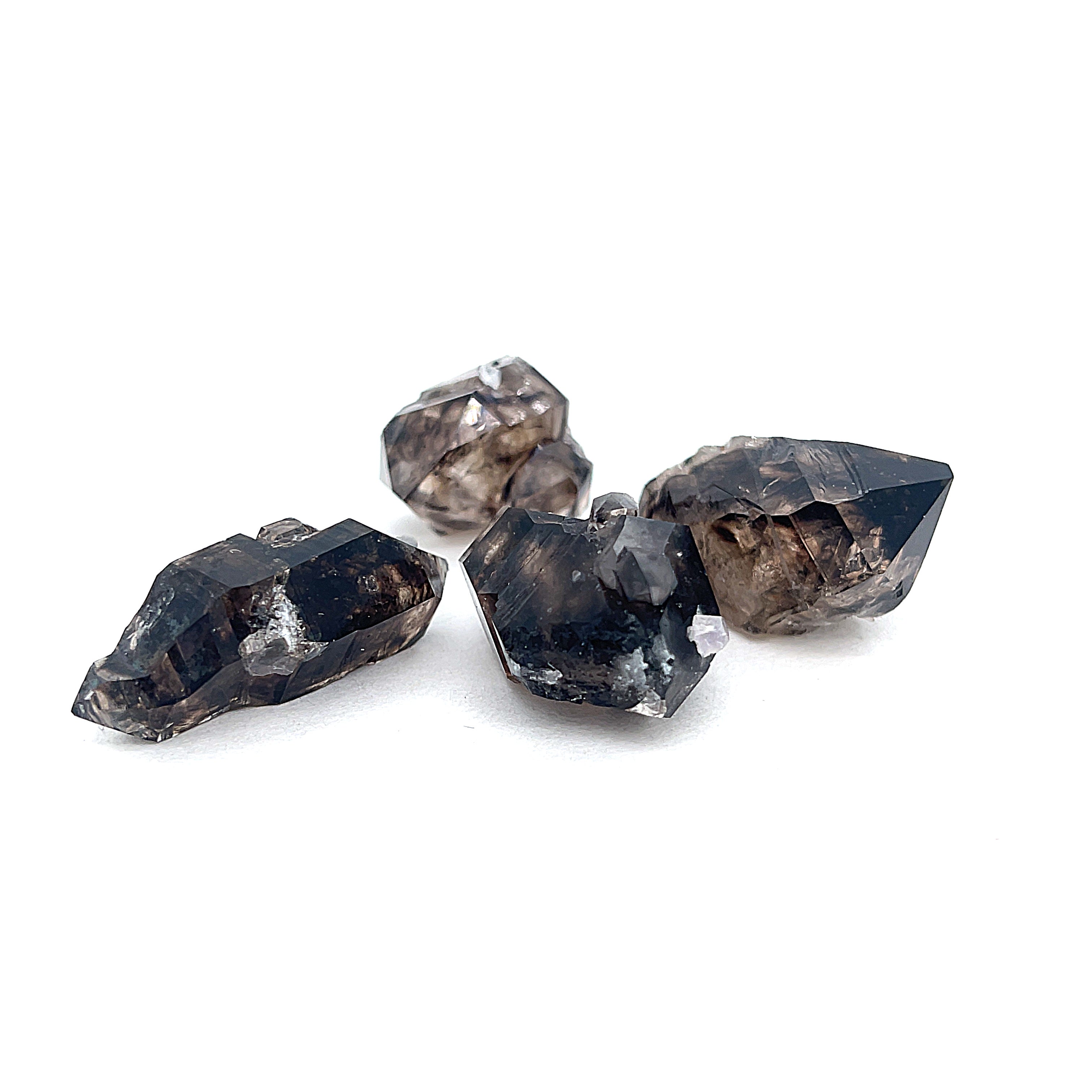 A collection of raw Smokey Quartz gemstones with a dark, smoky appearance, displayed on a white background in a front view. 