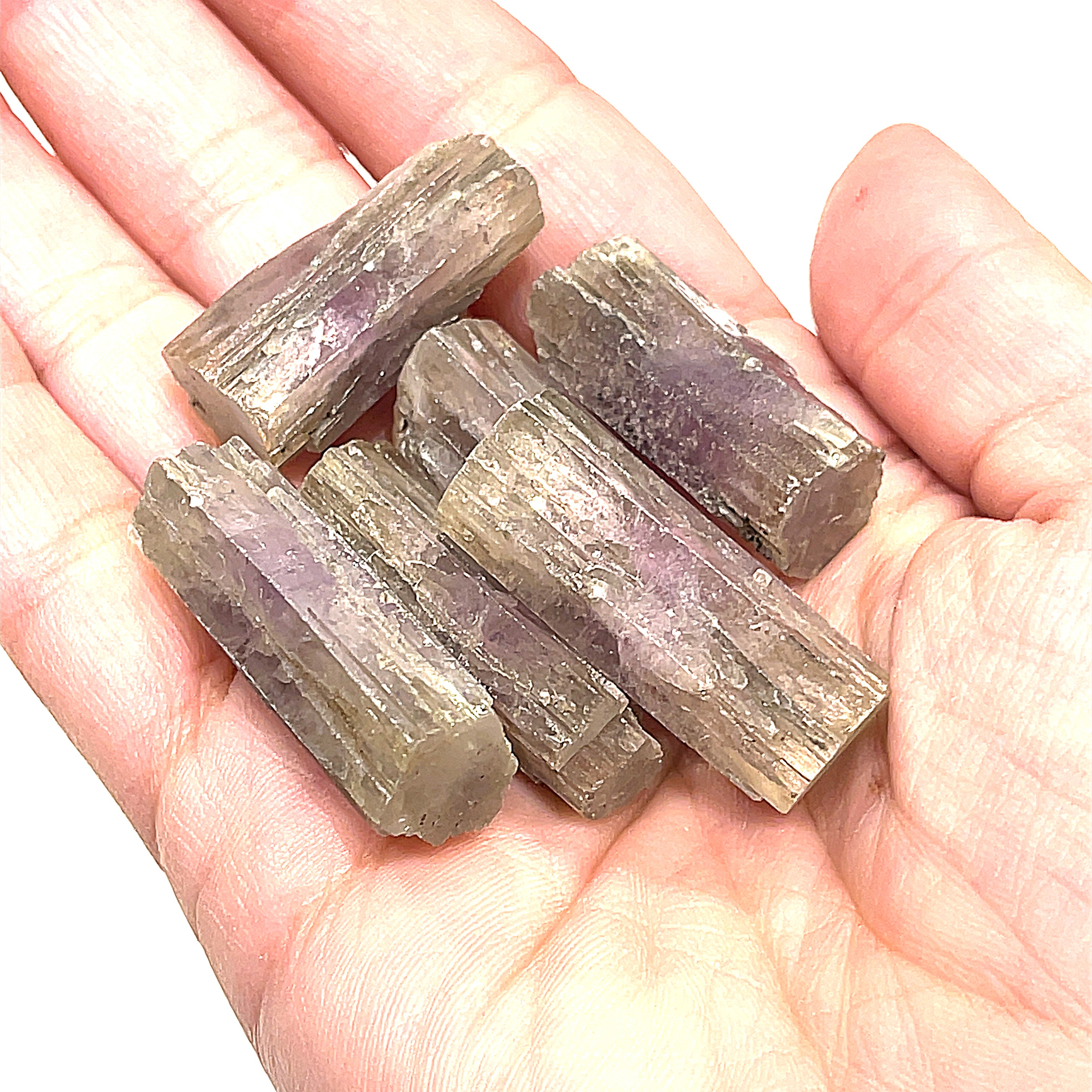 A collection of raw Spanish (Purple) Aragonite gemstones displayed in a models palm on a white background, front overview.