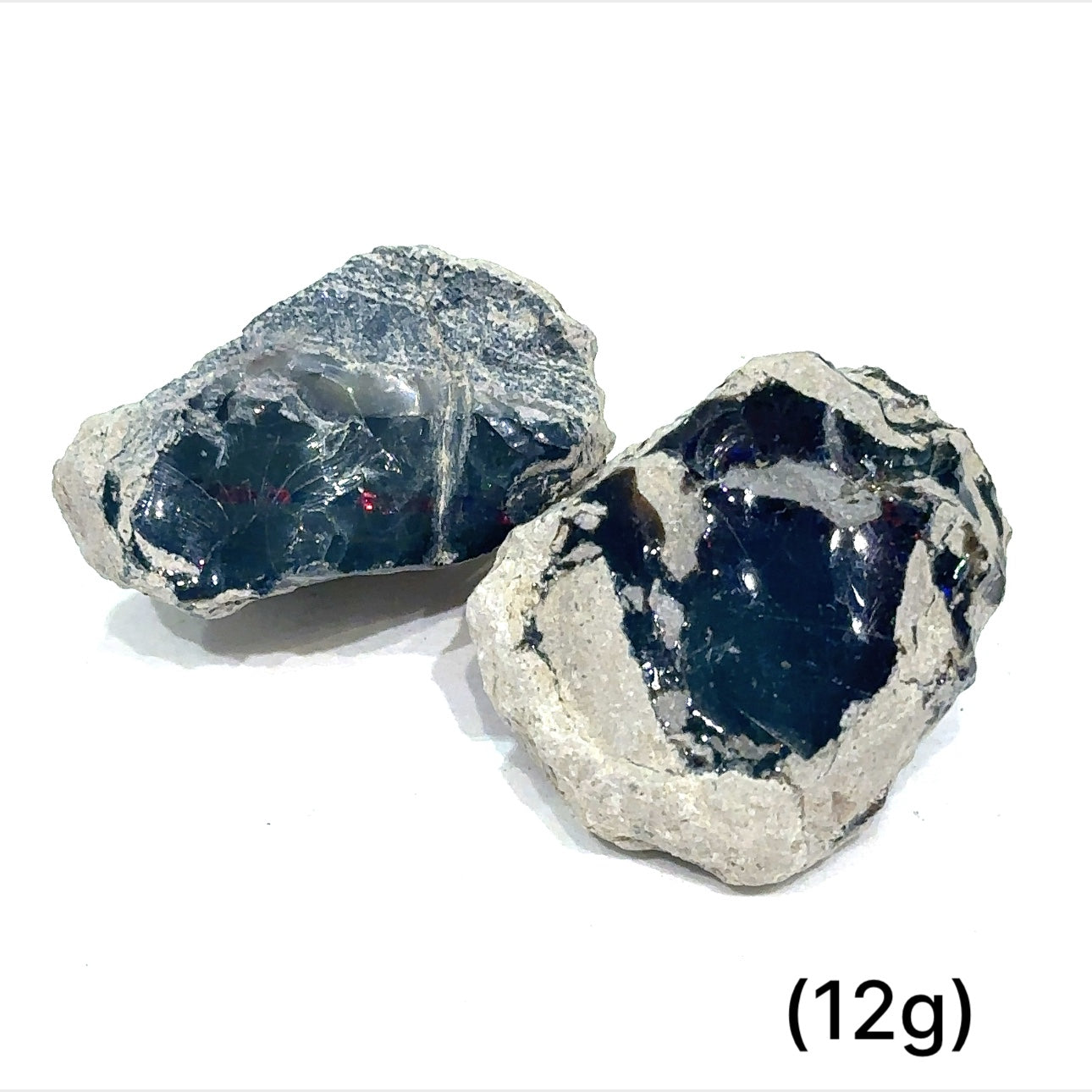 A collection of raw black Ethiopian opal gemstones with varying colors, displayed on a white background, 12g.