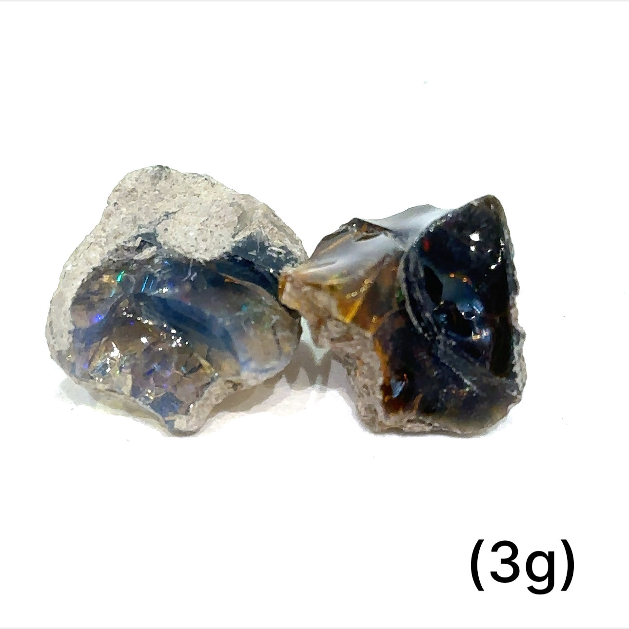 A collection of raw black Ethiopian opal gemstones with varying colors, displayed on a white background, 3g.