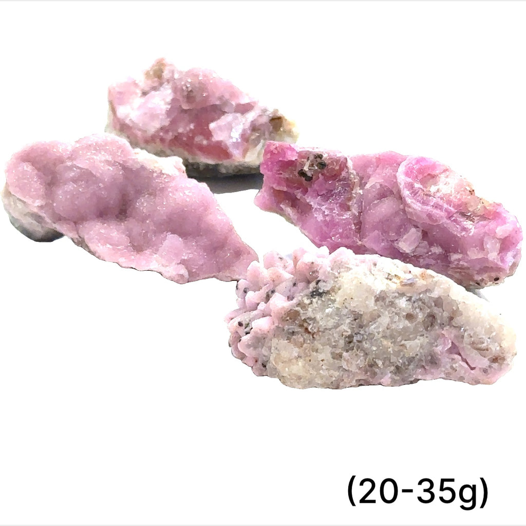 A collection of raw cobalt calcite gemstones with a pinkish hue, showing a rough, unpolished texture, and varying in size. The text indicates the weight range of 20-35 grams. on white background, front view