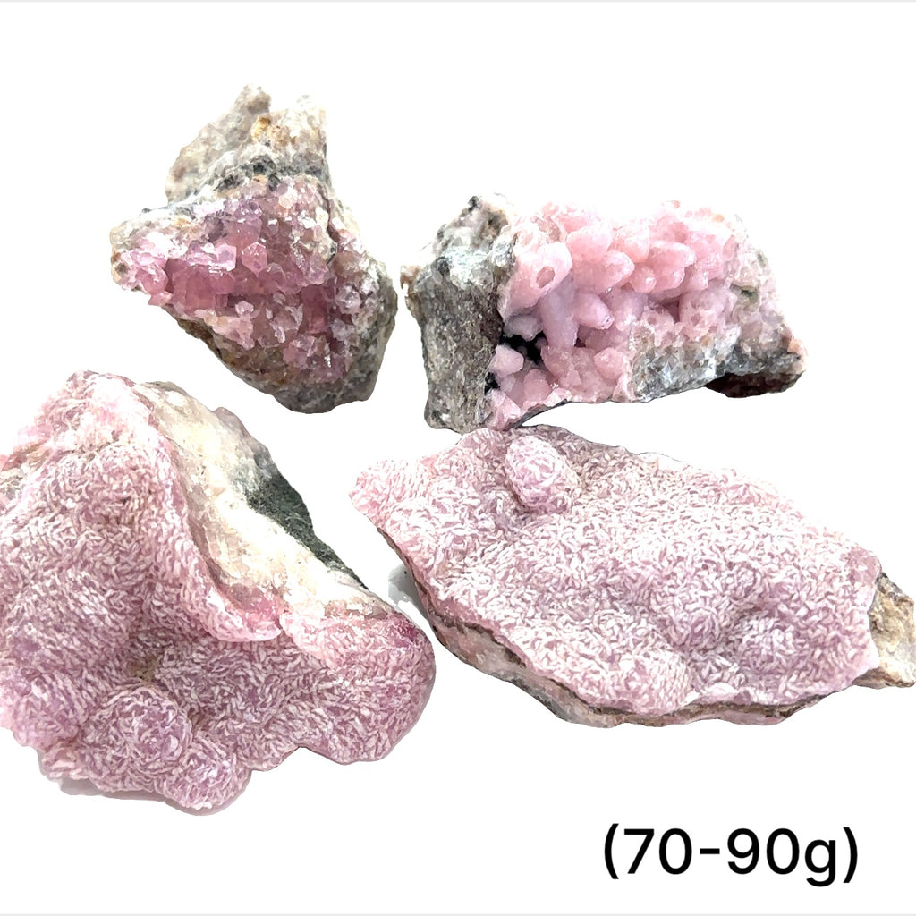 A collection of raw cobalt calcite gemstones with a pinkish hue, showing a rough, unpolished texture, and varying in size. The text indicates the weight range of 70-90 grams. on white background, front view
