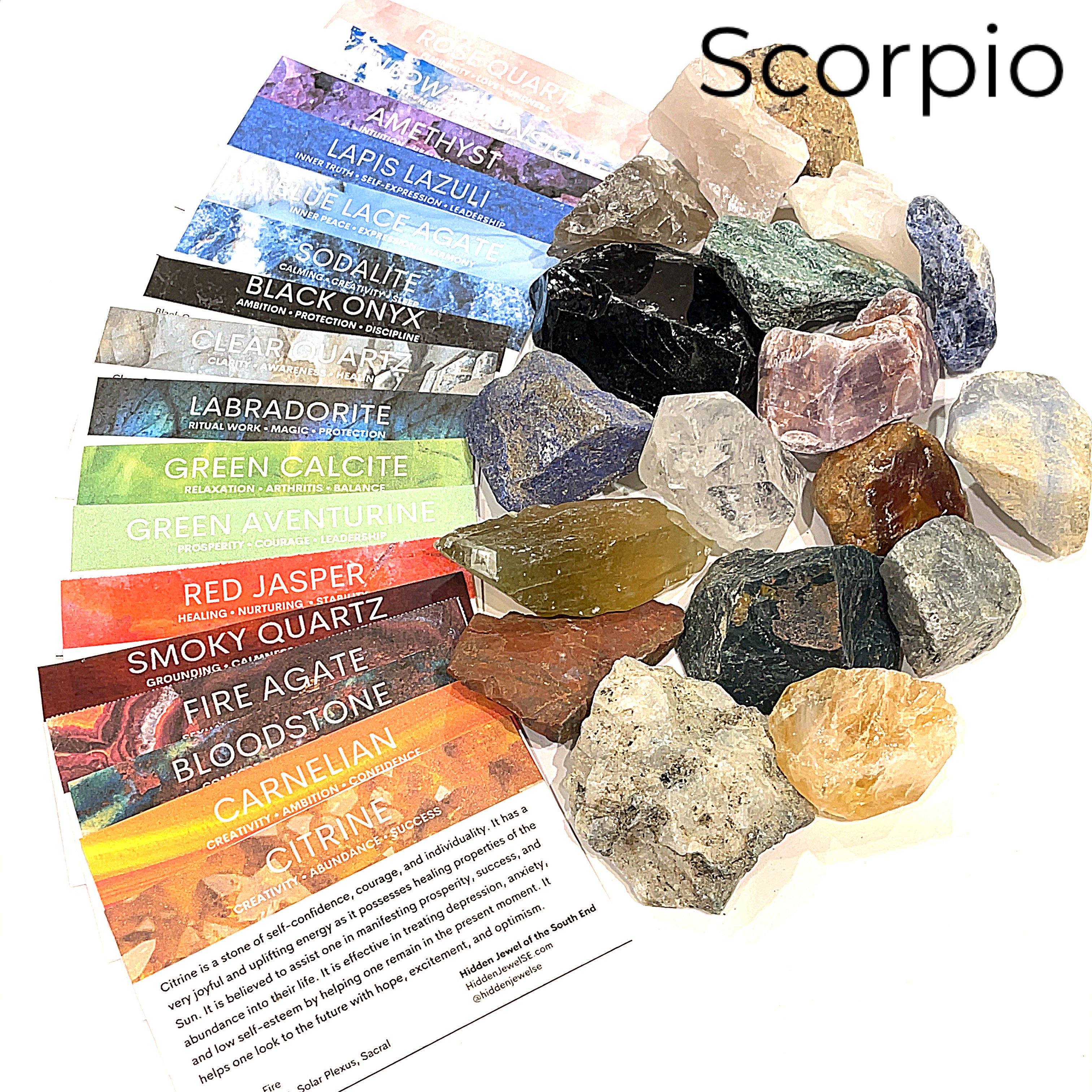A collection of raw gemstones spread out, each labeled with its type, such as Aquamarine, Amethyst, and others. The label at the top says 'Scorpio'.