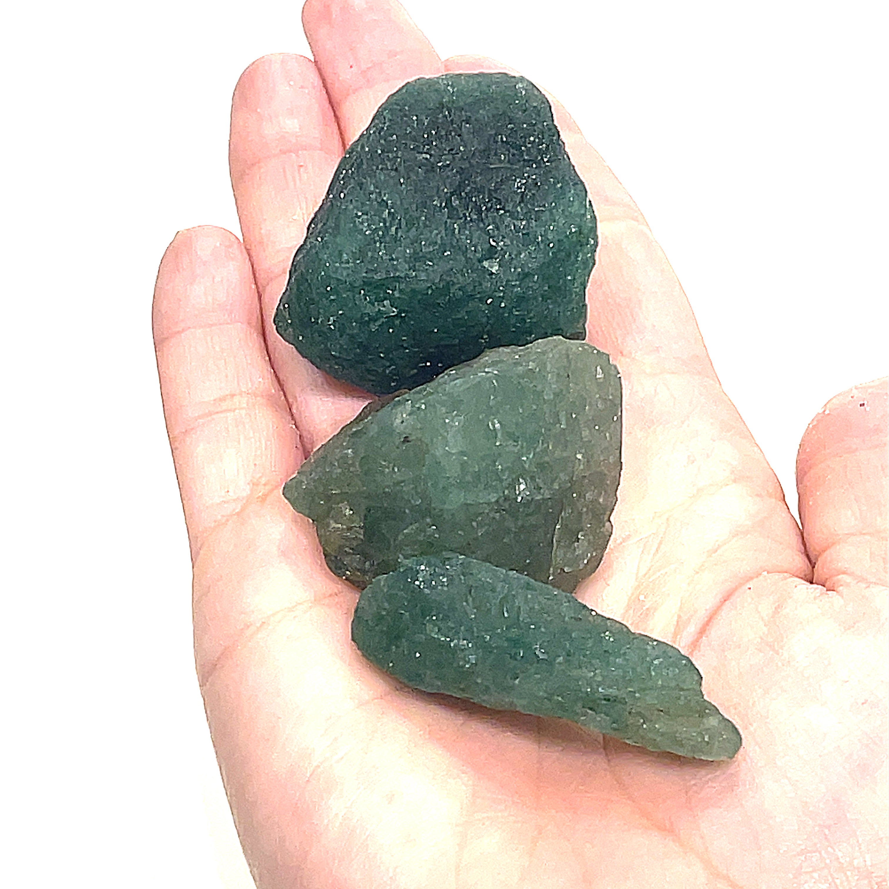 A collection of raw green tanzurine gemstones on a models hand against a white background, front overview. 