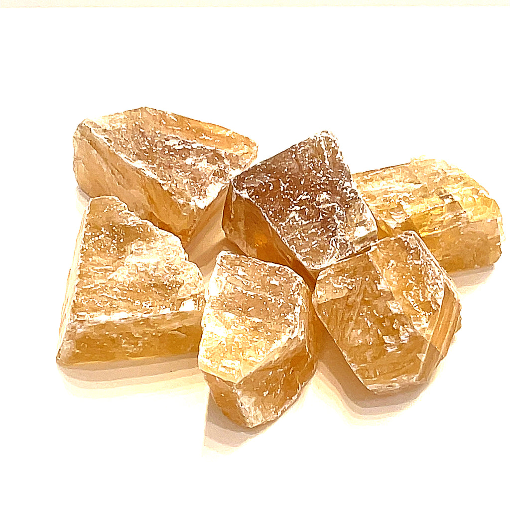 A collection of raw honey calcite gemstones displayed on a white background, front view.