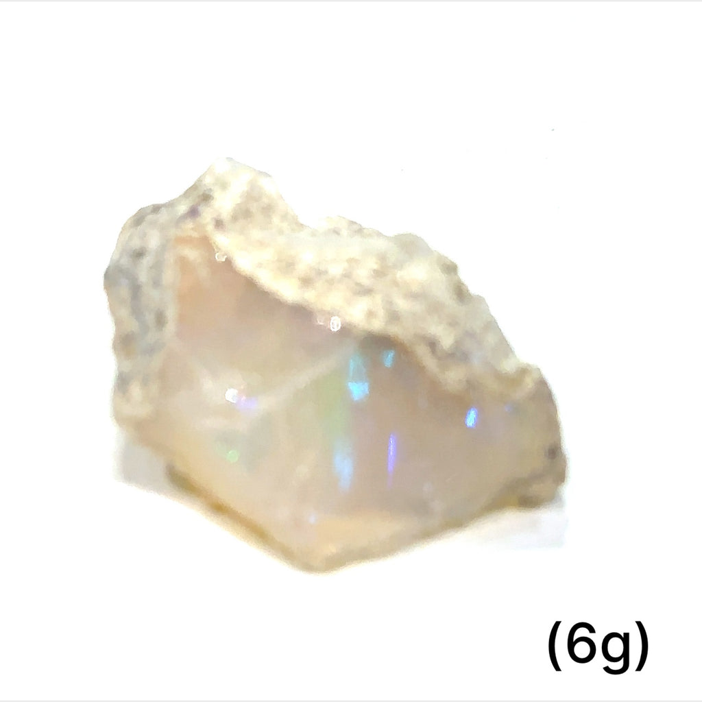 A collection of raw white Ethiopian opal gemstones with varying colors, displayed on a white background, 6g.