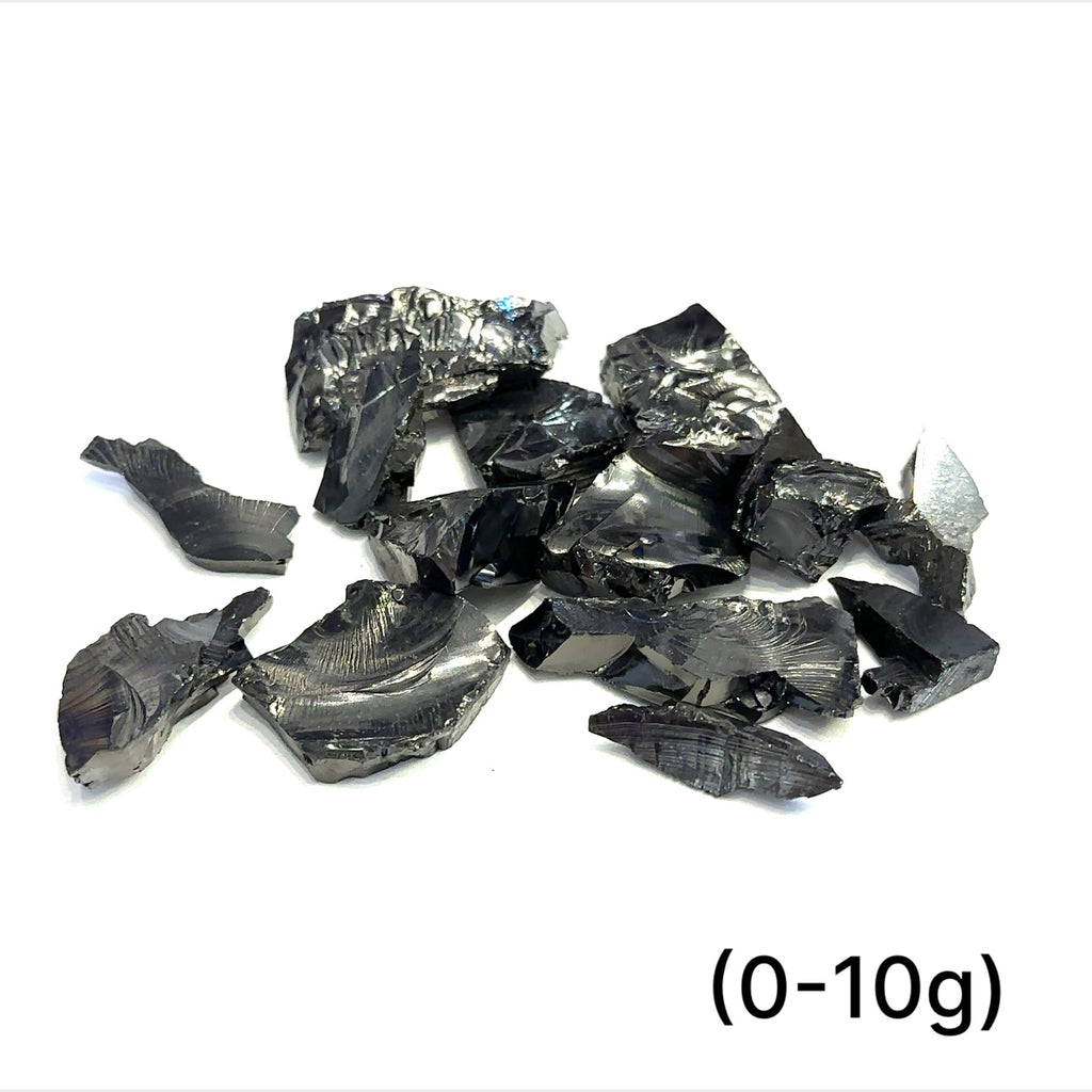 A collection of small raw Elite Shungite gemstone chunks (0-10g) on a white background, front overview. 