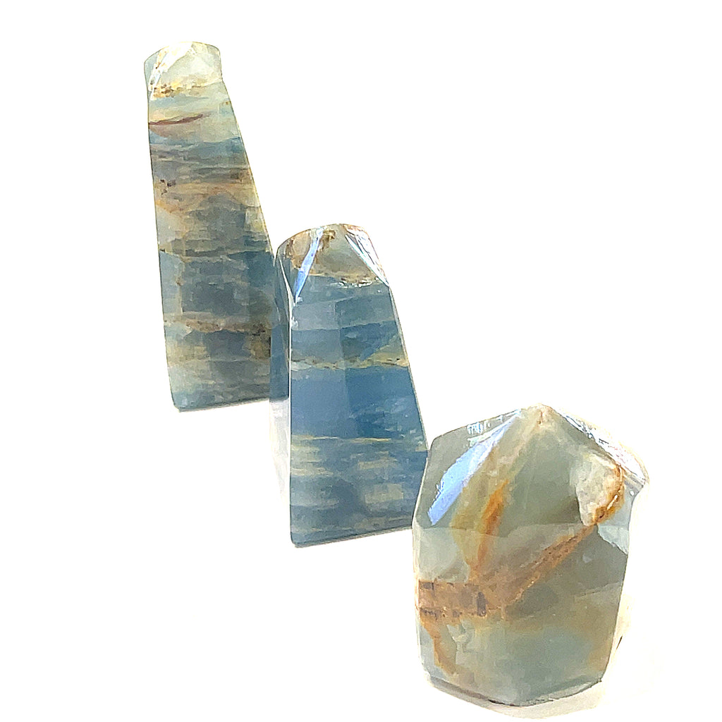 A collection of small sizes of  blue onyx gemstone towers displayed in a group on a white background, front overview.