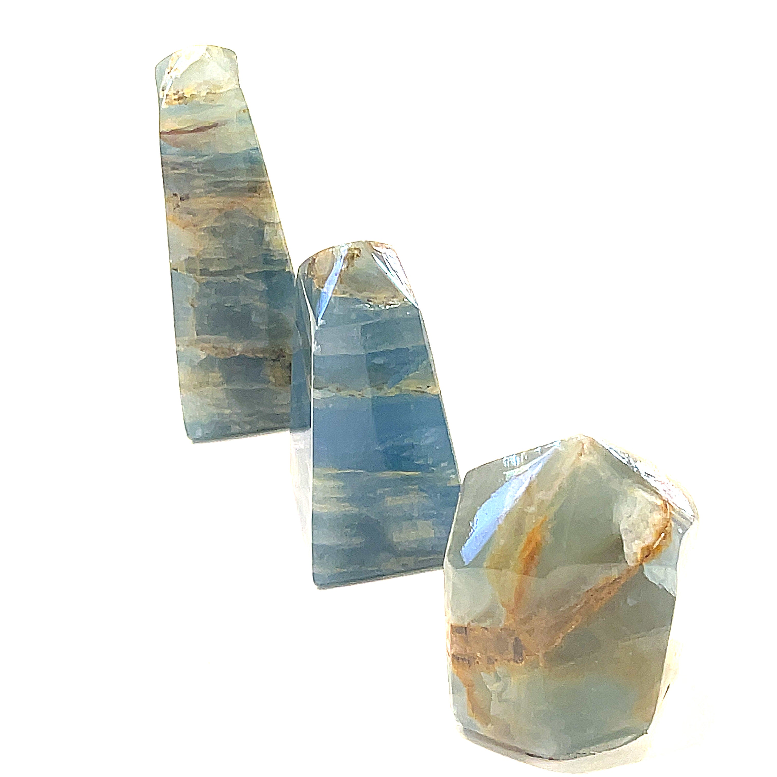 A collection of small sizes of  blue onyx gemstone towers displayed in a group on a white background, front overview.