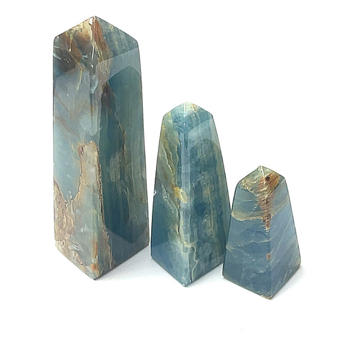 A collection of three of differernt blue onyx gemstone towers displayed in a group on a white background, front overview.