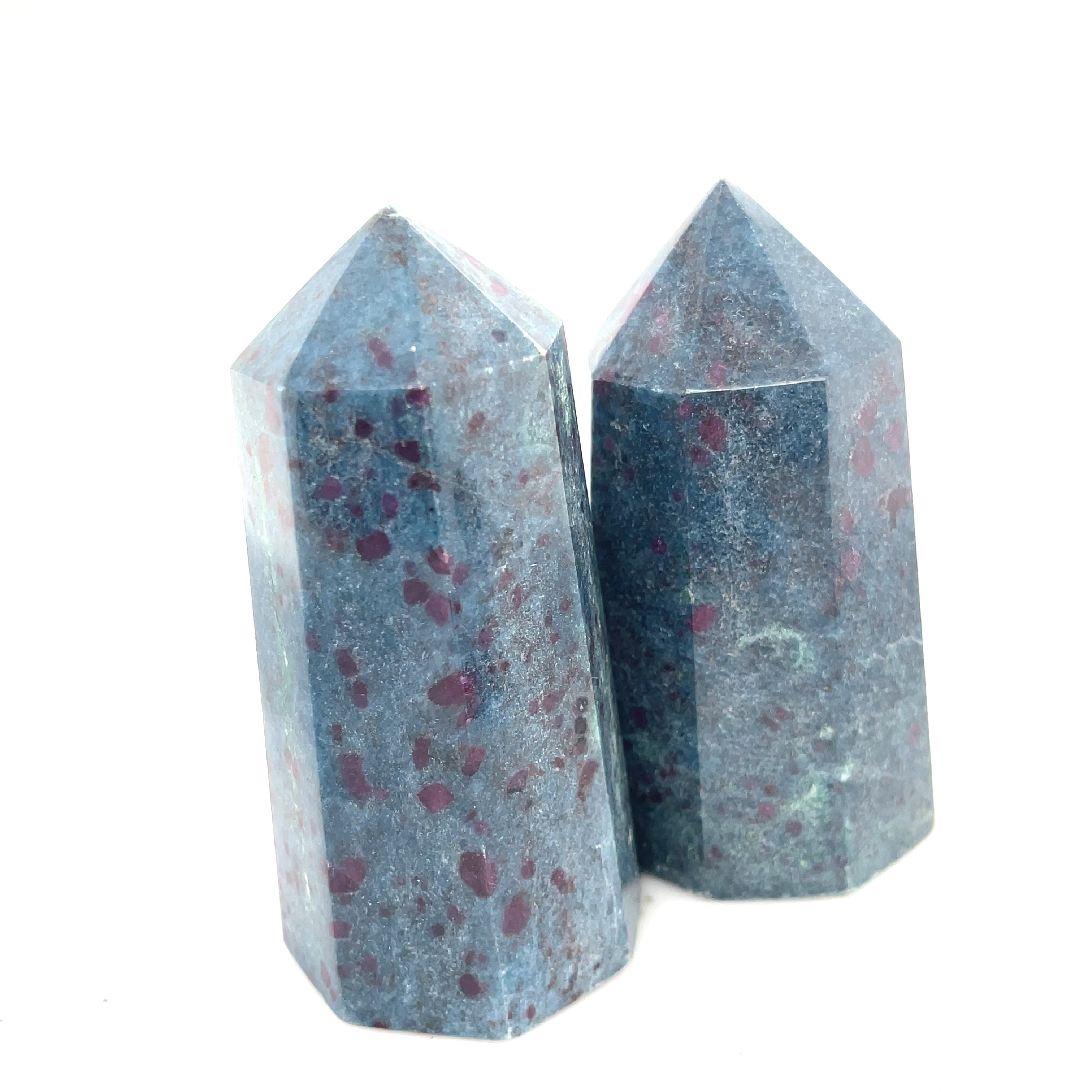 A collection of two Ruby Kyanite gemstone towers with a deep blue color and red speckles, displayed on a white background, front close up overview.