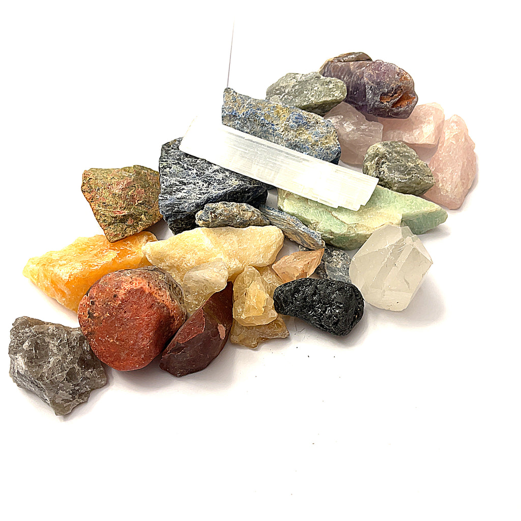 A collection of various raw gemstones from the Chakra bag. The gemstones are colorful and displayed against a white background in a front overview.