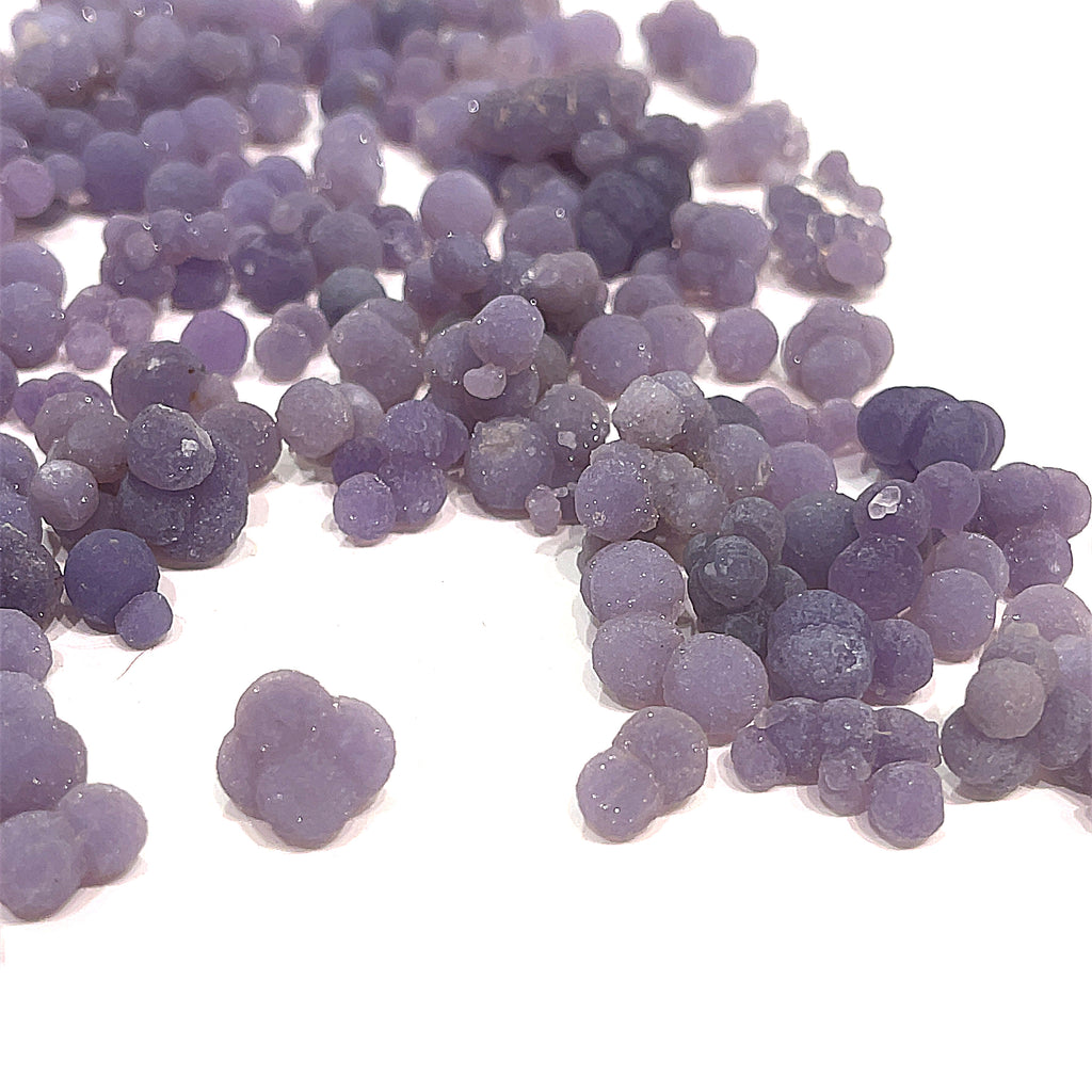 A collection of xs grape agate gemstone on a white background, front close up overview. 