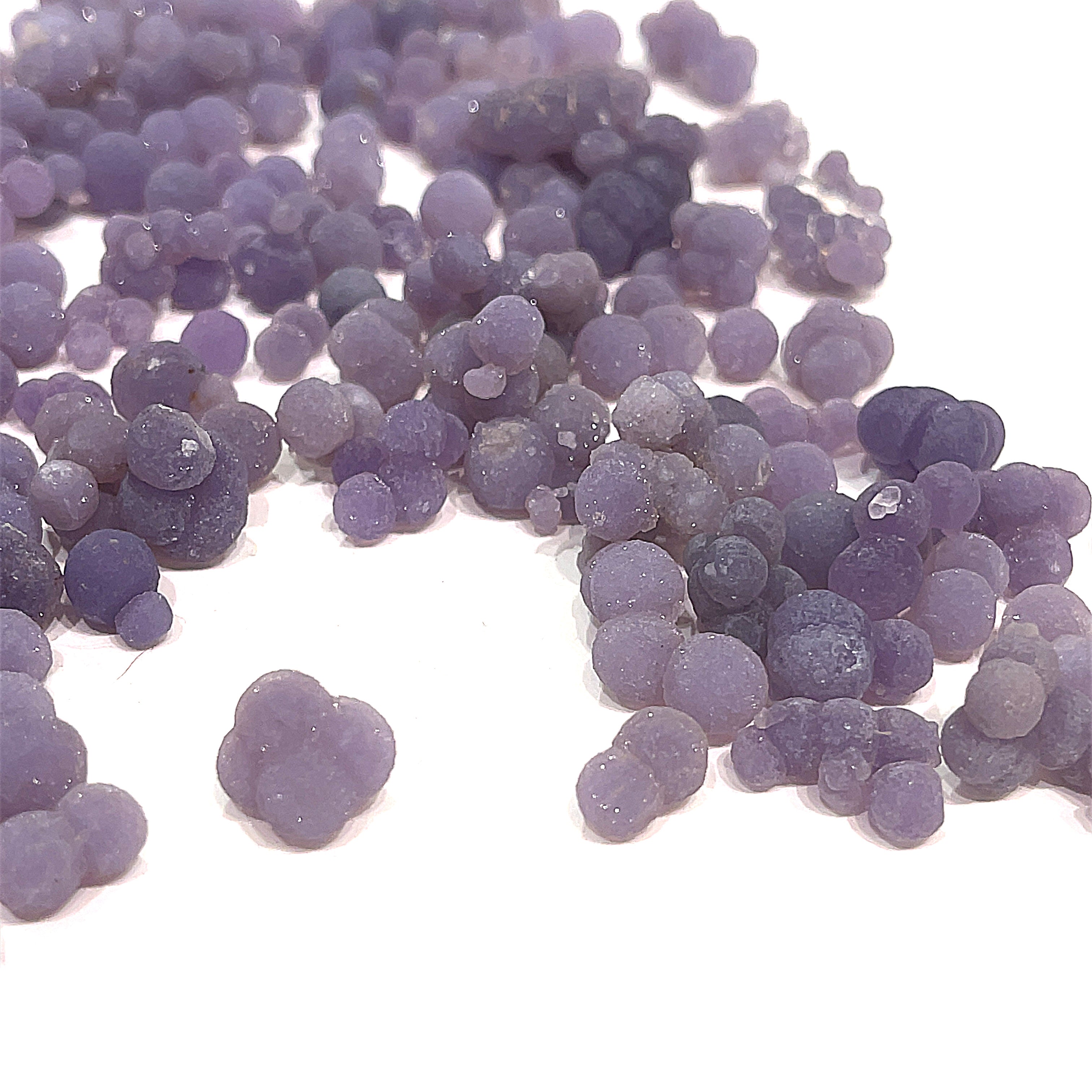 A collection of xs grape agate gemstone on a white background, front close up overview. 