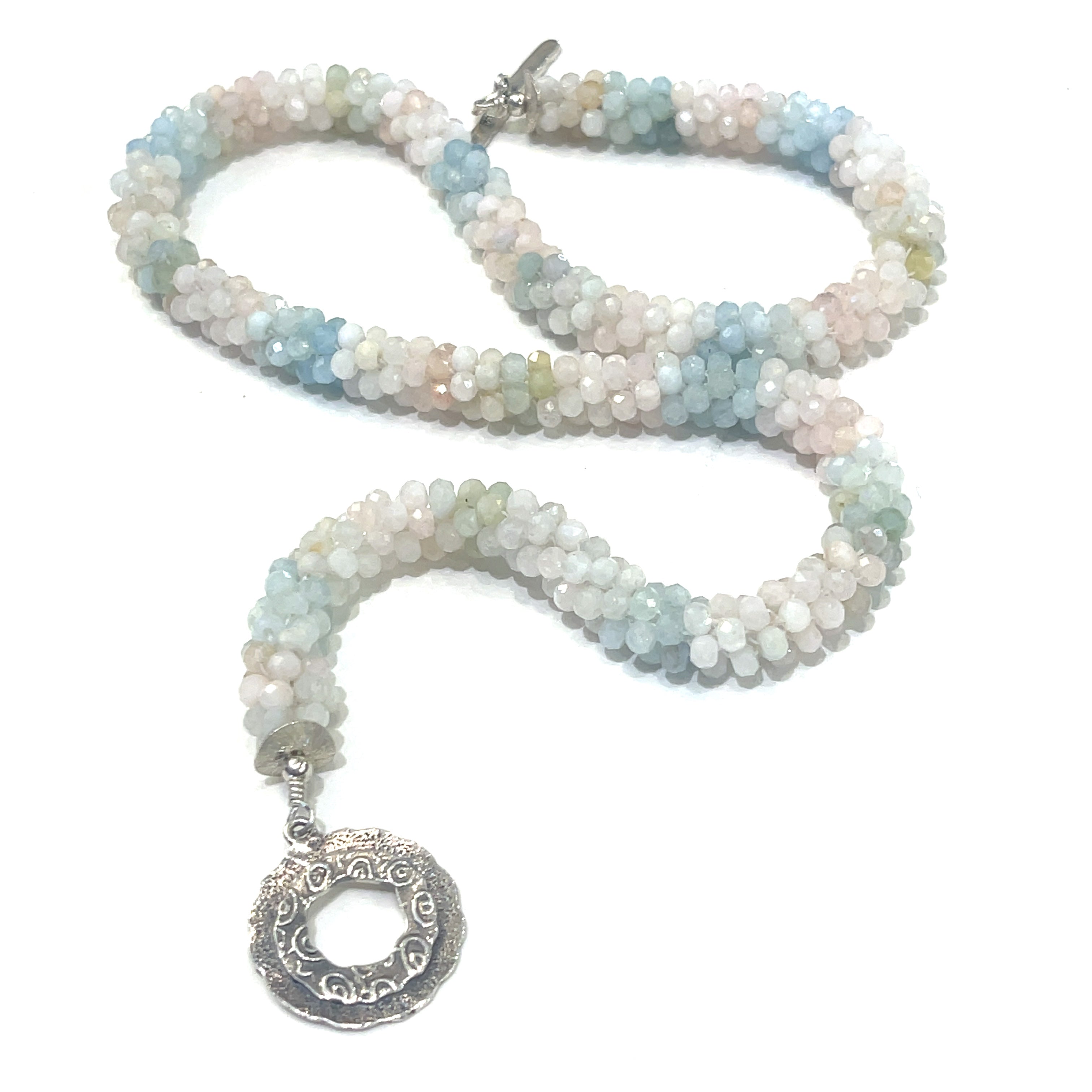 A crocheted morganite gemstone necklace with a variety of colorful beads and a sterling silver decorative toggle on a white background, a  center, long overview. 