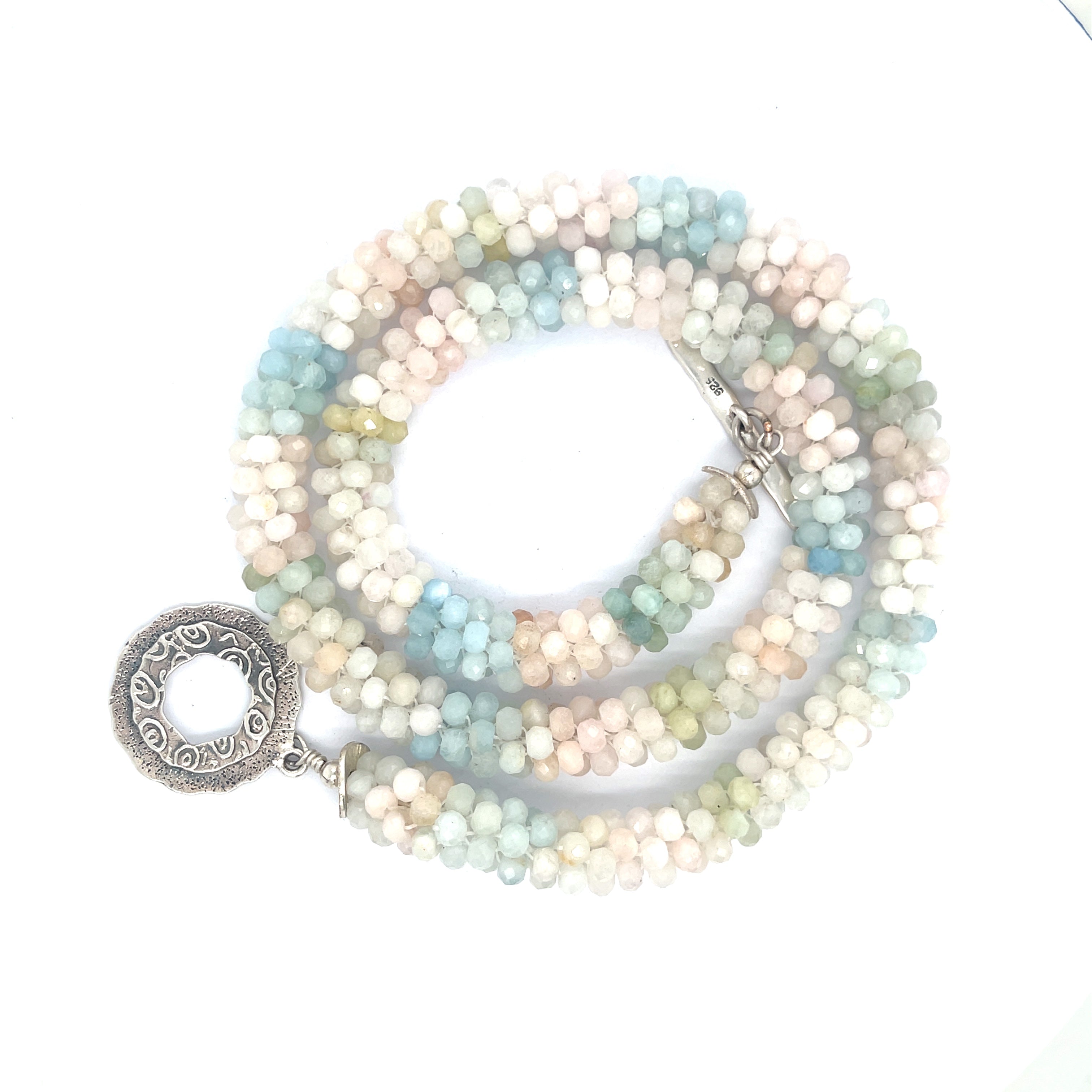 A crocheted morganite gemstone necklace with a variety of colorful beads and a sterling silver decorative toggle on a white background, a spiral center overview. 