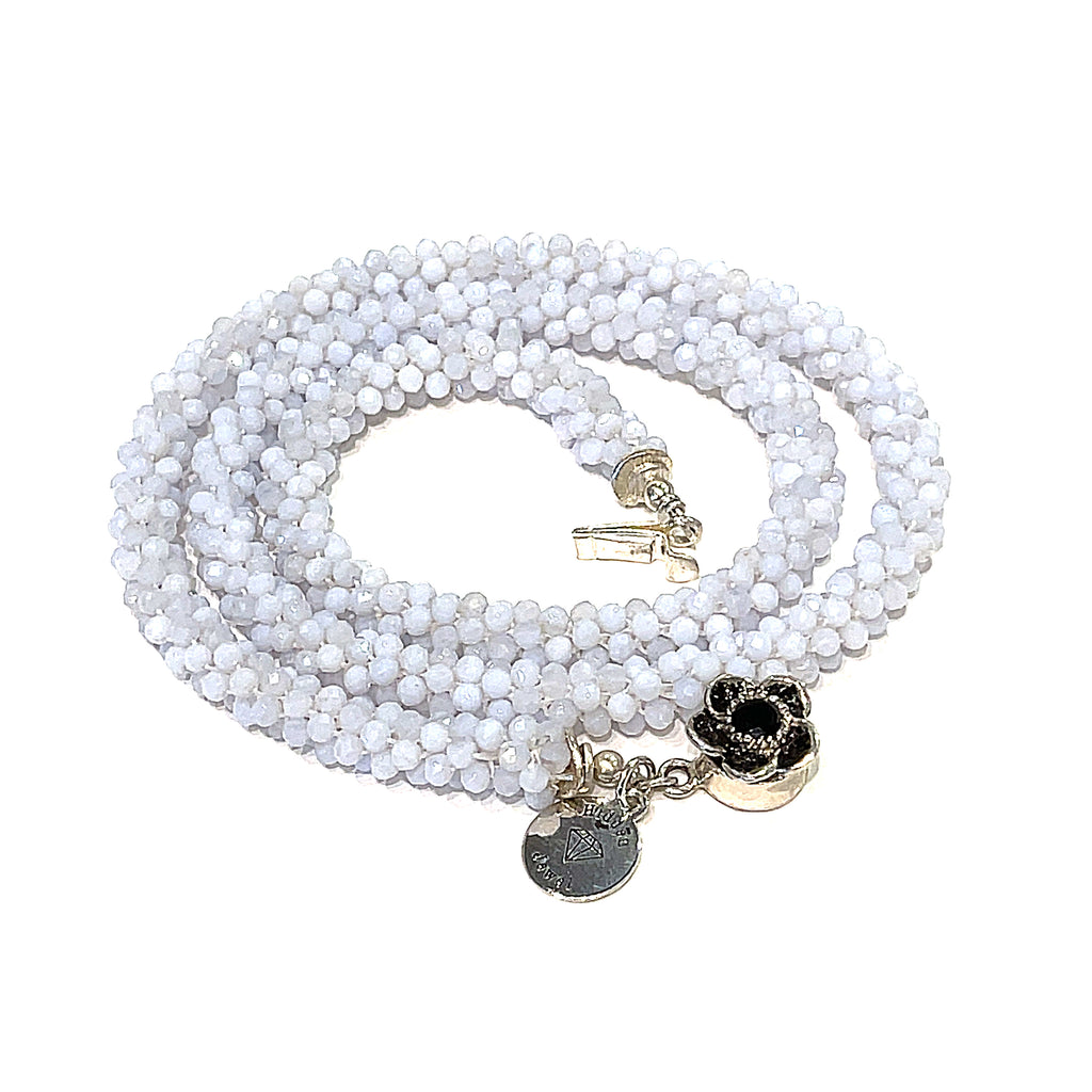 A crocheted necklace made with blue chalcedony gemstones on a white background, spiral, front overview.