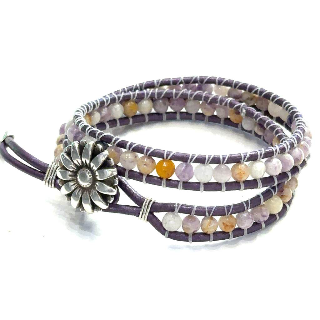 A double leather wrap bracelet made out of purple flower agate, featuring a floral button, and measuring 15.5 inches in length. On a white background button left angle view.