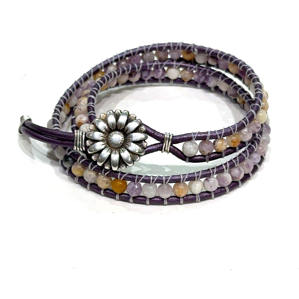 A double leather wrap bracelet made out of purple flower agate, featuring a floral button, and measuring 15.5 inches in length. On a white background button overview.