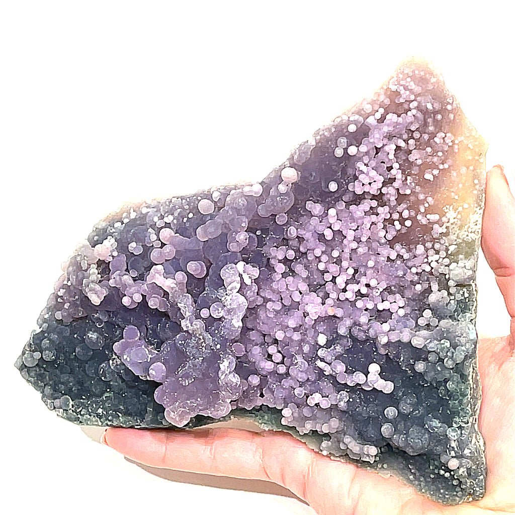 A extra large grape agate gemstone  on a  models hand on a white background, front close up overview. 