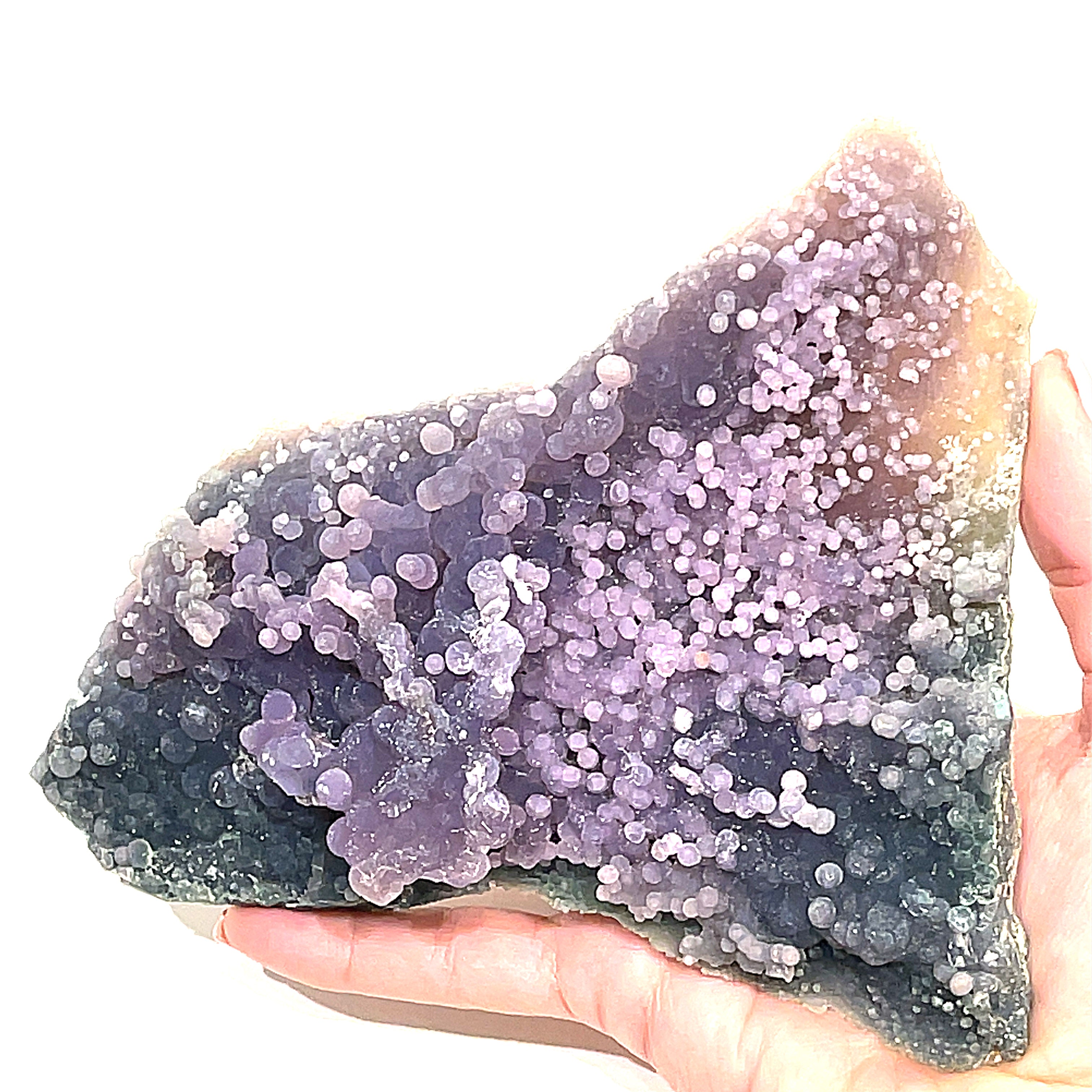 A extra large grape agate gemstone  on a  models hand on a white background, front close up overview. 