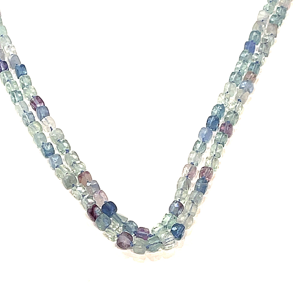 A fluorite gemstone knotted necklace with a sterling silver toggle clasp, beaded on silk beading cord, hanging up overview on a white background.