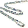 A fluorite gemstone knotted necklace with a sterling silver toggle clasp, beaded on silk beading cord, long front overview on a white background.