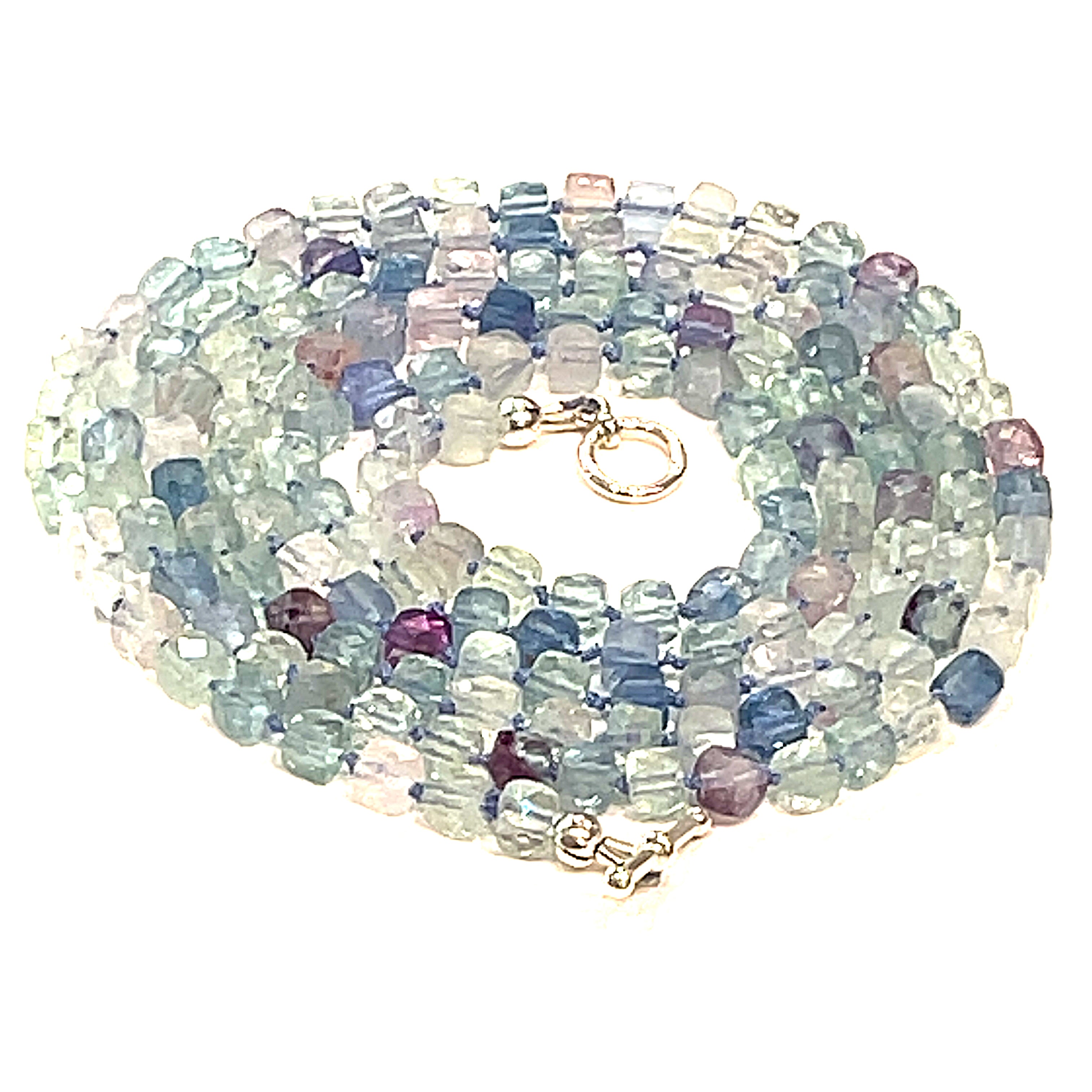 A fluorite gemstone knotted necklace with a sterling silver toggle clasp, beaded on silk beading cord, spiral close up overview on a white background.